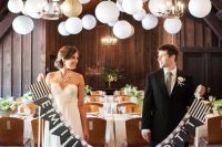 a wedding reception space styled with white balloons and gold paper lamps, with white blooms and greenery is a pretty and cool space