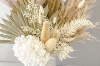 an airy wedding centerpiece of white hydrangeas, bunny tails, dried fronds and leaves is a textural and very creative idea