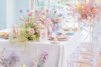 an iridescent wedding reception space with bold blooms and baby’s breath, with statement fronds and pastel place settings