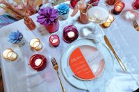 an iridescent wedding table setting with pink, blue and other touches, with candles, a blush plate and a colorful menu is wow