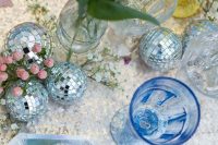 an iridescent wedding tablescape with disco balls, blue and yellow glasses, pink cutlery, iridescent chargers is wow