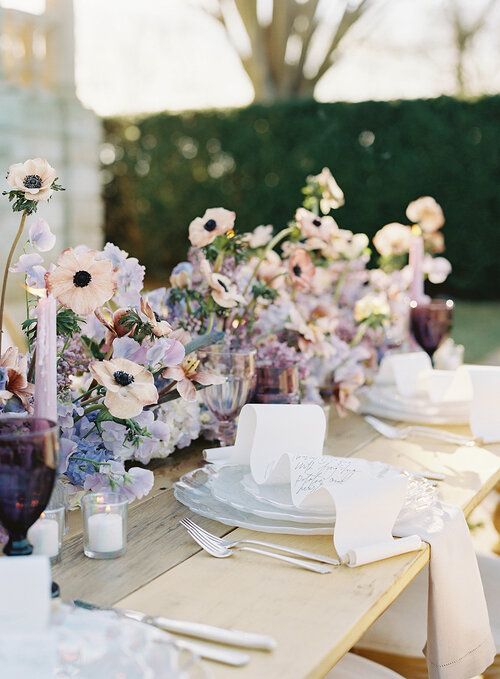 an iridescent wedding tablescape with iridescent blooms of blush and lilac blooms, lilac candles and purple glasses is wow