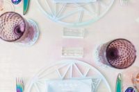 an iridescent wedding tablescape with iridescent wedding chargers, blue napkins, iridescent cutlery and purple glasses
