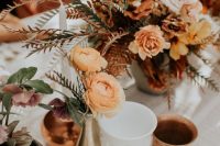bold boho fall wedding centerpieces of orange, blush and rust blooms, greenery, bold foliage and candles around are cool
