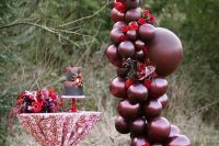burgundy balloons, red blooms and greenery for a bold wedding decoration over the dessert table is a very statement idea