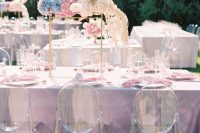 iridescent wedding tablescape with a lilac tablecloth, pink napkins, an eye-catchy iridescent floral arrangement over the table