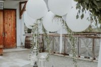 lovely and simple wedding outdoor decor with candle lanterns and white balloons and greenery is a chic and stylish idea