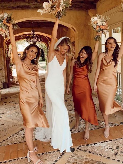 orange and gold slip midi bridesmaid dresses with cowl necks and asymmetrical skirts, nude shoes and statement earrings