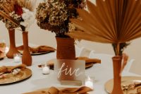 pretty modern boho fall wedding centerpieces of terracotta vases, dried fronds, blooms and grasses are very cool and chic