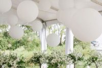 white balloons over the wedding ceremony space and white blooming trees make it look very airy and beautiful