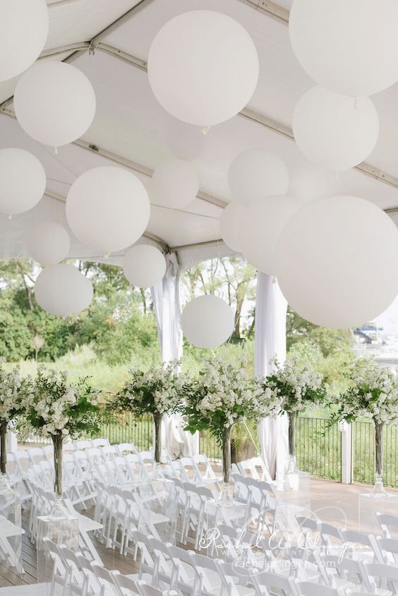 white balloons over the wedding ceremony space and white blooming trees make it look very airy and beautiful
