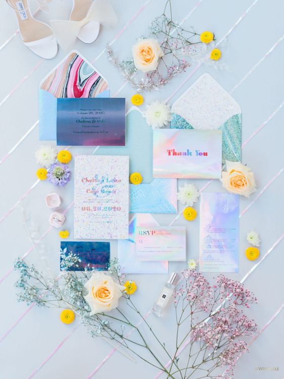 an iridescent wedding invitation suite with colorful letters, with pretty blooms and greenery is a lovely idea to rock