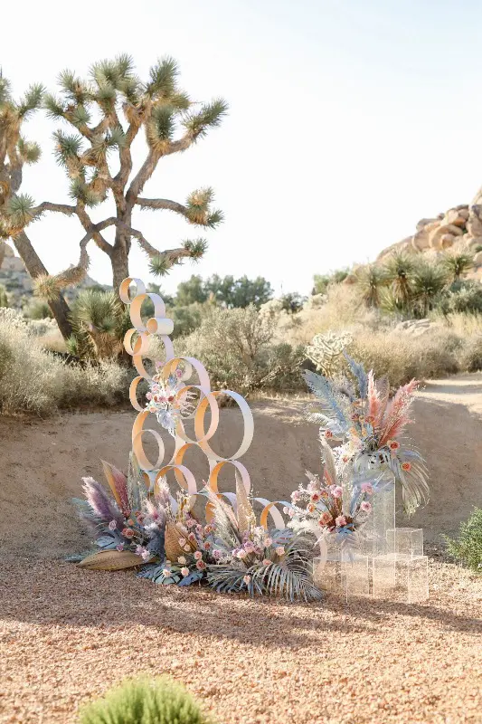 a chic iridescent wedding altar of rings, with bright grasses, fronds, leaves and blooms on acrylic stands is a very fresh idea