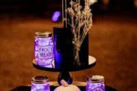 14 a black wedding cake decorated with dried blooms, jars with purple lights and a Jack Skellington pumpkin is wow