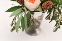 14 a pretty and simple winter wedding centerpiece of a shiny vase, greenery, blush peony roses and pinecones is a very cool and lovely idea