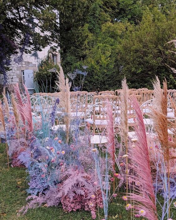 an iridescent wedding aisle decorated with bold spray painted blooms, foliage and pampas grass is amazing