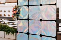 18 an iridescent holographic wedding backdrop decorated with pink, orange blooms and greenery is a stylish solution for an iridescent wedding