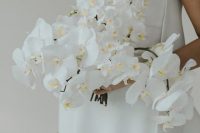 21 a lush and cascading white orchid wedding bouquet looks jaw-dropping with a minimalist wedding dress and lovely baroque pearl earrings