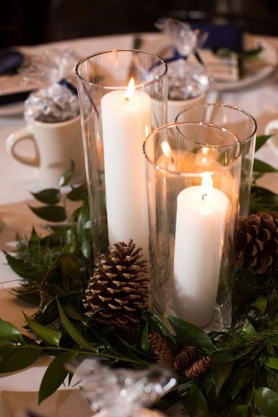 an inspiring winter wedding centerpiece of greenery, pinecones and pillar candles in tall glasses is a great idea for winter