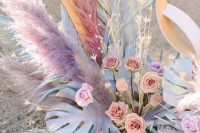 22 a pretty iridescent floral arrangement of bold spray painted leaves, blush and lilac blooms, pampas grass, fronds, lights is wow