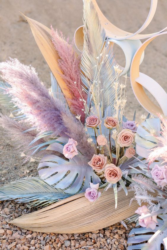 a pretty iridescent floral arrangement of bold spray painted leaves, blush and lilac blooms, pampas grass, fronds, lights is wow
