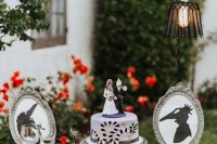 28 a Tim Burton wedding cake with themed cake toppers and small themed artworks plus greenery and blooms are adorable