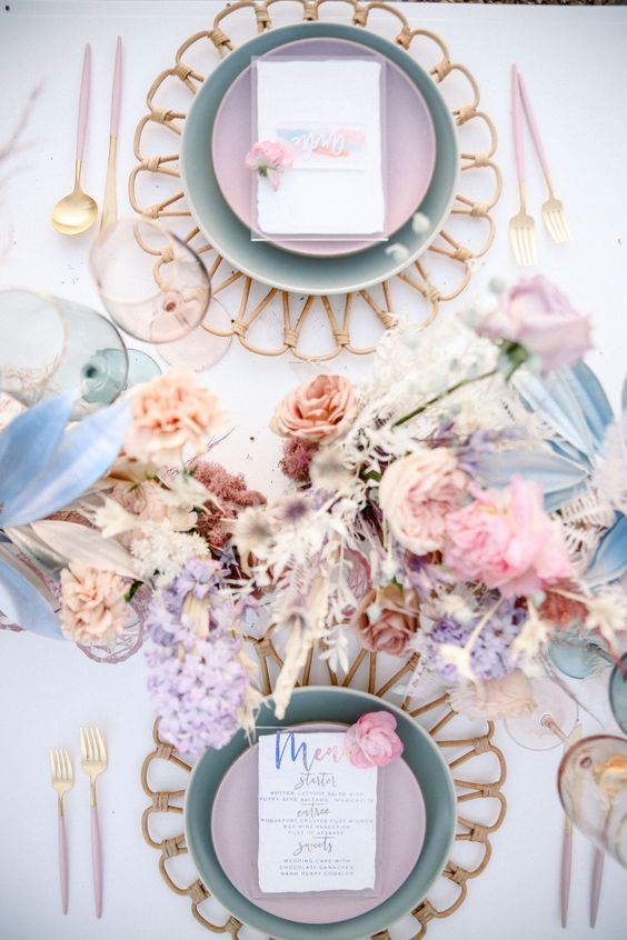 an iridescent wedding tablescape with pretty pastel florals and grasses, blue and lilac plates, pink cutlery and glasses