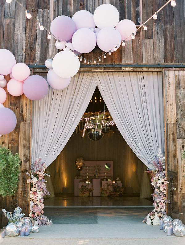 beautiful iridescent wedding barn decor with pleated curtains, blush and lilac blooms, disco balls and lilac candles, matching balloons