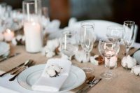 31 a neutral winter wedding tablescape with a burlap runner, cotton buds, pillar candles, white linens is cozy