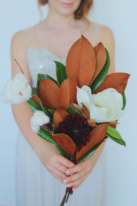 a beautiful southern wedding bouquet of magnolia leaves, magnolias, dahlias and cotton is a very out of the box idea that you may try