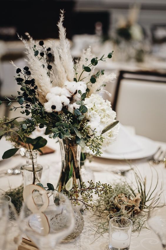 a beautiful wedding centerpiece of dried blooms, white hydrangeas, eucayptus, pampas grass and cotton is perfect for a boho wedding