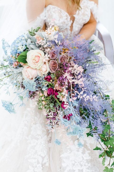 a bold cascading iridescent wedding bouquet with lilac, blush, blue, fuchsia and iridescent blooms and greenery