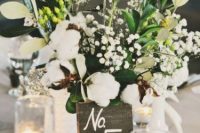 a bright and relaxed wedding centerpiece of greenery, cotton, billy balls and white blooms plus a reclaimed wood number
