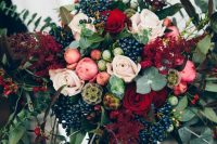 a bright fall wedding bouquet of pink, deep red and blush blooms, greenery and dark foliage, berries and seed pods looks very spectacular and will make a statement