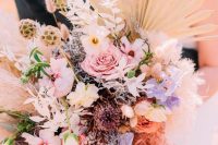 a bright iridescent wedding wedding bouquet of pink, neutral and lilac blooms, dried foliage, seed pods and fronds is wow