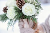a chic and neutral wedding bouquet of white roses, fern and greenery plus pinecones is a gorgeous idea for a rustic winter wedding