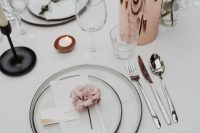 a chic minimalist wedding tablescape with elegant white linens, white plates with black edges, white blooms and candles