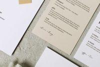a chic white and tan wedding invitaiton suite with black letters and monogram tags is a cool idea for a minimalist wedding, and with plenty of detail