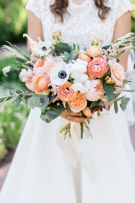 a colorful garden wedding bouquet of coral, peachy, blush blooms, white anemones, cotton, greenery and twigs is a beautiful idea