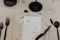 a contrasting minimalist wedding tablescape with neutral plates, black cutlery candlesticks and dried blooms and grasses