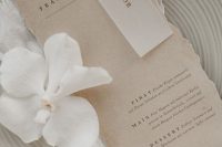 a delicate place setting with greige plates and a greige menu with a raw edge plus neutral linens is a lovely idea