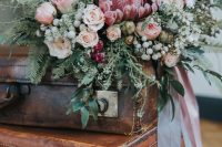a delicate winter wedding bouquet of blush roses and peony roses, a pink king protea, various textural greenery and neutral berries is amazing