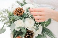 a delicately and lovely winter wedding bouquet of white roses, baby’s breath, evergreens and eucalyptus is an amazing winter idea