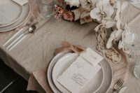 a lovely greige and blush wedding tablescape with beautiful and textural linens, white orchids and roses, neutral candles and speckled plates