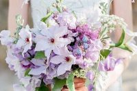 a lovely iridescent wedding bouquet with blush, purple and blue blooms and some foliage is a gorgeous idea