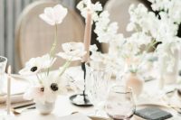 a minimalist and ethereal neutral wedding tablescape with neutral linens, plates, blush candles and white and blush floral arrangements
