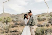 a minimalist geometric wedding arch placed right in the center of the desert is suitable for both a desert and a minimalist wedding