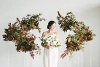 a minimalist wedding altar of acrylic stands with bold leaves and greenery is a beautiful idea for a fall minimalist wedding