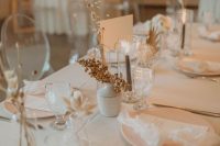 a natural and minimalist wedding table setting with all neutral everything, dried blooms, berries and grey candles is a stylish idea