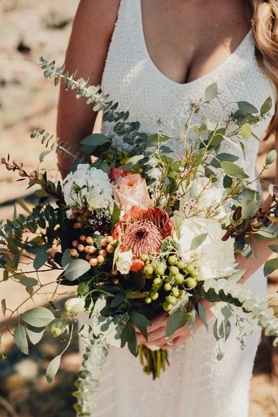 a neutral wedding bouquet of white and blush blooms, greenery, various types of berries is a lovely idea for a spring or summer bride